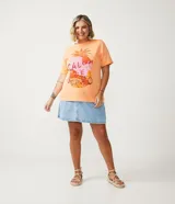 Remera color durazno de algodón con cuello redondo y mangas cortas. Presenta un estampado de piña con detalles de lentejuelas y la frase "Calor de Verão".