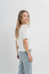 Remera tejida de manga corta, color gris claro, con escote en V y calce relajado. Presenta terminaciones acanaladas en mangas y ruedo.