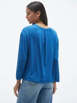 Blusa azul con estampado abstracto en blanco y negro, de mangas largas.