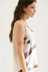 Musculosa blanca con estampado abstracto en tonos marrones y celestes, con cuello redondo y sisas con ribete en color crudo.