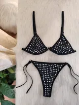 Conjunto de bikini negro con tachas plateadas. El corpiño es de corte triangular con breteles regulables y aro metálico central. La bombacha es tipo colaless con tiras laterales regulables.