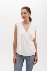 Musculosa blanca cruzada con escote en V que se ata alrededor del cuerpo. Confeccionada en algodón suave. El detalle de volados en 3D recorre el frente y los hombros.