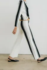 Pantalón de punto color crudo con rayas verticales negras a los costados.