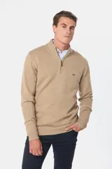 Buzo tejido de lana color beige, con medio cierre metálico y cuello alto. Tiene un pequeño logo bordado en el pecho.