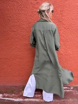 Sobrecamisa larga verde militar de viscosa con cuello camisero, cierre frontal con botones y mangas largas con puños abotonados. Presenta tajos laterales.
