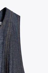Vestido midi de denim azul oscuro, con cuello redondo y sin mangas. Presenta costuras a contraste y cierre trasero con cremallera oculta.