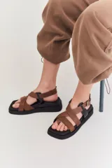 Sandalias con plataforma negra y tiras cruzadas en tonos beige y marrón.
