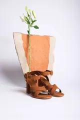 Sandalias de cuero color marrón con tiras cruzadas en el empeine, pulsera con hebilla al tobillo y tacón cuadrado.