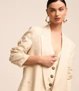 Blazer largo color beige confeccionado en viscosa y lino, con cuello solapa, bolsillos y forro estampado a rayas.