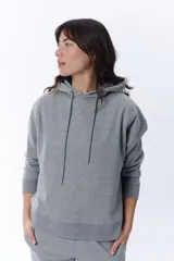 Sudadera con capucha (hoodie) de color gris melange, con diseño liso y cordones ajustables en el cuello. Presenta puños y pretina acanalados.