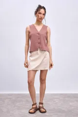 Chaleco de punto sin mangas, color rosado, con escote en V y cierre frontal de tres botones marrones.