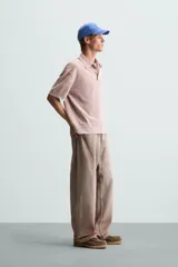 Polo de hombre color rosa, corte relaxed fit, tejido de punto con textura bouclé y mezcla de algodón. Tiene cuello solapa, cierre frontal con botones, manga corta y acabados en rib.