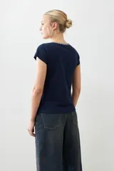 Remera blanca de algodón con escote en V y bordado en el borde. De corte recto y mangas cortas.