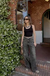 Pantalón jean gris oscuro de corte wide leg con diseño de líneas diagonales en la parte superior.