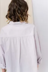 Camisa color crema de algodón liviano, calce oversize, con cuello camisero, cierre abotonado, mangas largas con opción de arremangado y dos bolsillos frontales con solapa.