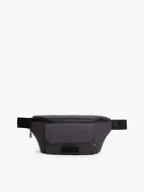 Riñonera o cangurera de color gris oscuro, confeccionada en poliuretano, con correa ajustable y cierre de hebilla. Presenta un compartimento principal con cremallera y un bolsillo exterior frontal con solapa.