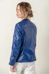 Campera azul de cuero ovino italiano, con cuello redondo, cierre frontal con broches ocultos, bolsillos laterales y detalle de capitoneado en puños y bolsillos.