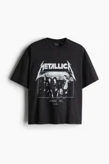 Remera negra de algodón con estampado del logo de Metallica y la imagen de la banda Damage Inc. 1986. Corte oversized con cuello redondo ribeteado, hombros caídos y bajo recto.