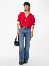 Blusa roja con estampado floral, escote en V con lazos, mangas cortas abullonadas con volantes en los puños y corte cropped.