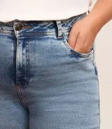 Pantalón de jean azul claro, modelo flare, con cintura elástica, trabillas para cinturón, bolsillos delanteros y traseros, y botón en forma de flor.