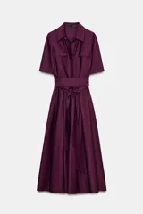 Vestido camisero midi color morado oscuro, con cuello solapa, manga corta y bolsillos de plastrón con solapa en el pecho. Incluye un cinturón ancho del mismo tejido anudado a la cintura.