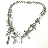 Collar plateado de cadena gruesa con dije de estrella calada, pin de gancho con tachas, cuentas y dijes colgantes.