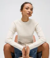 Suéter de manga larga color blanco hueso, confeccionado en punto texturizado con cuello redondo y puños y bajo acanalados. Contiene viscosa certificada en su composición.