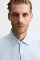 Camisa blanca de corte regular, cuello italiano, manga larga con puños abotonados y cierre frontal con botones.