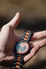 Reloj multifuncional para hombre, con caja de madera de sándalo rojo y acero inoxidable negro. La esfera es de madera de sándalo rojo con subdiales negros funcionales que ofrecen cronógrafo, indicador de 24 horas y fechador. La malla es de acero inoxidable negro con incrustaciones de madera de sándalo rojo.