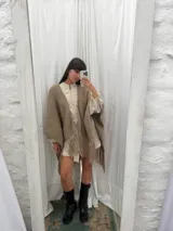 Ruana negra tejida a mano en lana merino con detalles de brillos y flecos.