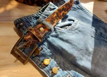 Cinto de cuero con estampado animal print y hebilla metálica dorada.