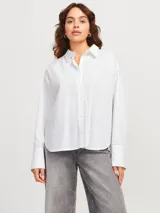 Camisa blanca de corte oversize con cuello clásico, cierre frontal con botones y pequeños brillantes plateados distribuidos por toda la prenda.