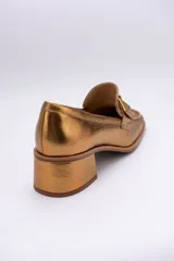Mocasines de cuero color peltre con taco cuadrado y aplique geométrico al tono.