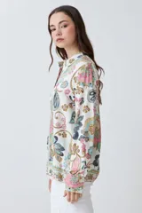 Camisa de manga larga con estampado de arabescos en tonos rosa, celeste, marrón y verde agua sobre fondo blanco. Tiene cuello clásico y cierre con botones.