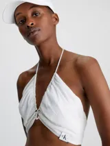 Blusa blanca con textura arrugada, escote halter y cierre anudado en la espalda.