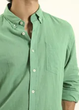 Camisa azul marino de lino y algodón, con cuello abotonado, manga larga con puños enrollados, bolsillo de parche en el pecho y cierre frontal con botones.