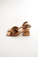 Sandalias plateadas de cuero, con tiras cruzadas sobre el empeine, pulsera al tobillo con hebilla y taco bajo cuadrado.