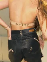 Top color beige de cuero descarne con flecos largos, detalles dorados y tirantes regulables.