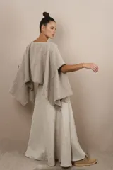 Poncho color beige con diseño a cuadros, cuello bote y terminaciones desflecadas. Tiene aberturas para los brazos en los laterales y detalles en cuero.
