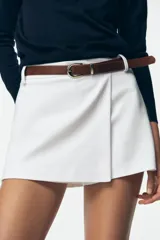 Falda pantalón blanca de tiro alto con cinturón marrón y delantero cruzado. Cierre lateral con cremallera oculta.