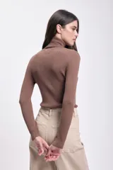 Polera de punto de color beige con cuello alto y manga larga, ajustada al cuerpo.