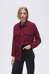 Camisa color borgoña de viscosa, corte holgado, con cuello camisero, cierre frontal con botones, mangas largas con puños abotonados y dos bolsillos con solapa en el pecho.