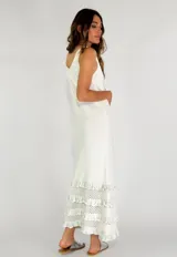 Vestido largo amarillo sin mangas con escote redondo y ruedo con tres volados de encaje.