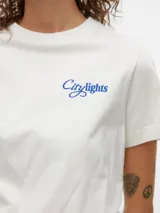 Remera blanca de algodón con cuello redondo y mangas cortas. Estampado pequeño en el pecho con la frase "City Lights" en color azul.