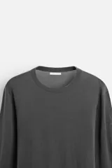 Jersey negro de lana con acabado mercerizado, corte relaxed fit, cuello redondo y manga larga con terminaciones en rib.