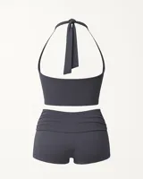 Top gris de cuello halter con espalda descubierta y detalle de aplique metálico dorado con el nombre de la marca.