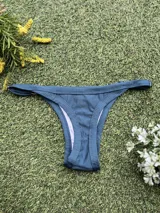 Conjunto de bikini color petróleo, de lycra acanalada, compuesto por un corpiño de triángulo fijo con breteles regulables y una bombacha colaless regulable con argollas metálicas.