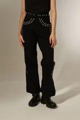 Pantalón negro de corte ancho con tachas plateadas en la cintura y laterales.