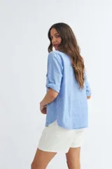 Camisa color crema de algodón con escote en V, mangas 3/4 con trabilla y dos bolsillos con solapa en el pecho.
