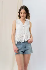 Chaleco blanco sin mangas con bordado floral y encaje calado. Presenta escote en V con terminación festoneada y cierre frontal con botones.